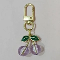 Detail view of purple resin cherry keychain with gold hardware and green enamel leaves - Gold Hook Purple Cherry (Two Leaves)