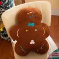 Gingerbread man plush pillow with embroidery details and bowtie on a chair - Chocolate Gingerbread Man / 45cm