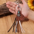 Western boho keychain with sunflower, turquoise and leather fringe tassels held in hand - Brown Embossed