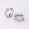 Star-shaped silver huggie earrings with white zircon stones on stone background - Wavy Star Shape / Silver