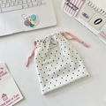 Close-up of white polka dot drawstring pouch with pink ribbons on a clean desktop - Medium / Light Pink Rope