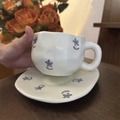 Macro detail of hand-painted floral ceramic coffee cup with textured finish and saucer - Blue Flower