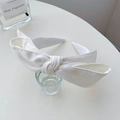 Elegant white satin headband with large bow detail on a minimalist white desk - Pure White Bow