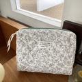 Dettaglio ravvicinato della borsa cosmetica trapuntata a fiori con zip verde menta - Grande Dimensione Floreale