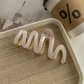 Detail view of wave-shaped pale pink acetate hair claw clip with pearlescent finish - Striped Pink