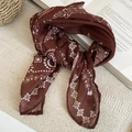 Nahaufnahme des braunen Seidenschals mit Paisley-Muster auf einem Buch im Vintage-Stil - Vintage Paisley-Stil / Braun Paisley