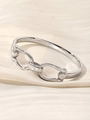 Detailed view of silver-tone double ring interlocking bangle on cream silk fabric - Silver