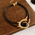 Detailaufnahme des goldenen geometrischen Anhängers mit schwarzem Stein auf Lederband - Halskette - Gold