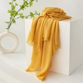 Minimalist yellow cotton linen scarf with fringe edges displayed on white stand - Bright Ginger