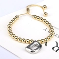Detail view of golden beaded bracelet featuring a silver balloon letter D charm and adjustable cord - Letter D