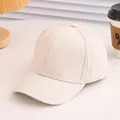Close-up of a plain off-white cotton baseball cap on a desk with warm ambient lighting - 52cm(Adjustable) / Off White