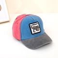 Close-up of red and blue color-block baseball cap with detailed dinosaur patch embroidery - Red/Blue/Dark Grey Spliced (E)