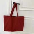 Detail view of large red canvas tote bag hanging on a door handle in a simple setting - Solid Dark Red