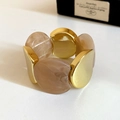 Close-up of minimalist acrylic bracelet with marble resin and polished gold metal parts - Gold Brown