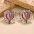 Detailed macro view of heart-shaped pink cat-eye stone earrings in silver metal setting - Pink