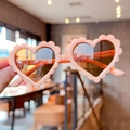 Close-up of pink heart-shaped sunglasses with stylish wavy edges for children - Pink