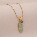 Detail of gold necklace with turquoise hexagonal pendant featuring bee and crescent moon - Light Green