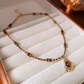 Macro detail of 18k gold tiger eye teardrop pendant with elegant beaded long chain - Brown Oval Irregular Necklace