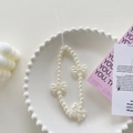 Minimalist pearl beaded phone strap featuring white gauze bows in a decorative ceramic dish - Pearl Bowknot Bracelet
