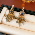 Detail of bohemian gold earrings with blue gemstones and grey-green crystal bead tassels - Blue Gold Tassel