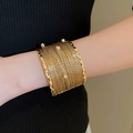 Dettaglio del bracciale multistrato dorato con cristalli scintillanti sul polso donna - 25# Bracciale-Oro