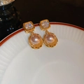 Detailansicht vergoldeter Perlenohrring mit Zirkonia auf einem weißen Porzellanteller - Champagner Gold Zirkon Perle (925 Silberstift)