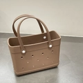 Close-up detail of a brown EVA beach tote bag featuring a perforated hole design and white rivets. - Brown