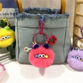Detail of colorful fluffy plush ball keychains with star hooks on a denim bag - Watermelon red