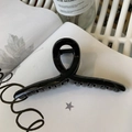 Glossy black twisted 13cm hair claw clip placed on a book for a chic hairstyle look - 13cm Hanger Type / Glossy Black