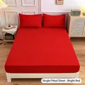 Solid red fitted sheet set including two matching pillowcases on a modern queen bed - Red