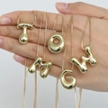 Golden 18K gold-plated bubble letter necklaces held in hand on white background - 14k / Letter M