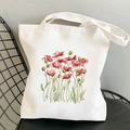 White canvas tote bag with red poppy flower print placed on a black metal chair - Red Poppy