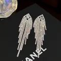 Primer plano de pendientes de borla plateados con diamantes de imitación brillantes - Aguja de plata
