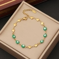 Detail of gold evil eye bracelet with heart links on a beige leather jewelry box - Green