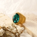 Close-up of vintage gold ring with large oval emerald gemstone and textured metal band - Gold Dark Green Gemstone
