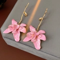Detail von Vintage-Ohrringen mit rosa Emaille-Blumen und Goldblättern auf grauem Samt - Rosa