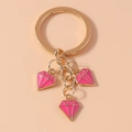 Detailed close-up of golden keychain featuring three pink diamond-shaped enamel pendants - Rose Red