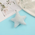 Dettaglio del ciondolo a stella in peluche azzurro con cordino argento su tessuto bianco - Celeste