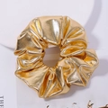Close-up of golden scrunchie with metallic luster fabric and elegant pleated texture - Gold