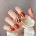Detail van amber gradiënt kunstnagels met een 3D-strikje en elegante parels - D-16 (Geleelijm-stijl)