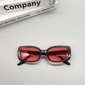 Flat lay of oval sunglasses featuring dark purple frames and transparent red lenses - Translucent Grey Red