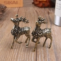 Coppia di sculture di cervi in rame vintage con dettagli floreali su superficie in legno - Piccolo Cervo Sika