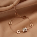 Dettaglio macro del bracciale a doppia catena in oro rosa con zirconi e ciondoli incisi - Cavigliera a Cilindro Oro Rosa con Zirconia