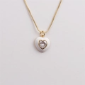 Detail of a gold heart pendant with white enamel and a sparkling heart zircon center - White