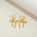 Elegant gold bow earrings with sparkling cubic zirconia set on a beige textured surface - Large Gold Bowknot