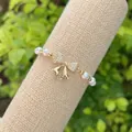 Macro detail of 18K gold-plated bow charm with sparkling crystals on a pearl bracelet - Style 4(4)