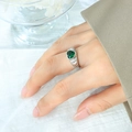 Anillo corazón plateado con piedra verde y tallados laterales visto en la mano - US 7 / Acero con piedra verde