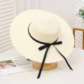 Elegant cream straw sun hat with black ribbon bow on wooden stand for beach vacations - Medium Brim Bow Creamy White