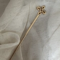 Elegante goudkleurige haarspeld met klaverknoop ontwerp op beige linnen achtergrond - Bloemstijl / 17cm / Goud