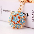 Macro-opname van gouden metalen hanger met blauwe emaille bloemen en goudkleurige kralen - Blauw
